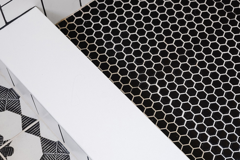 Omaha Home, Kitchen, Bathroom and Basement Remodeling - Hexagonal tiles with a bee pattern beneath a wooden cabinet with minimalist handles.